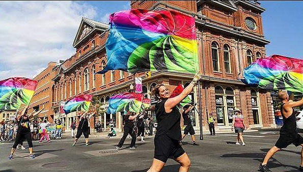SOTA performers en route in a parade with flags.