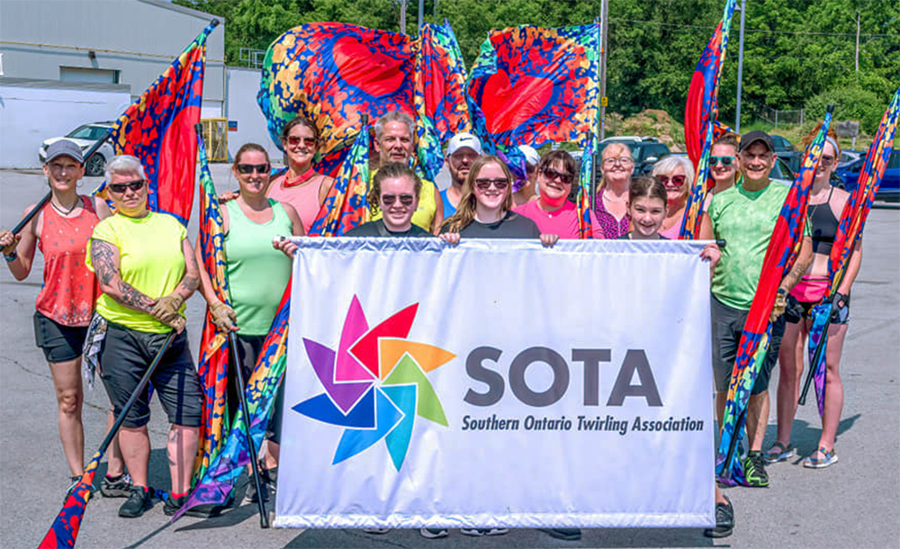 SOTA performers standing together behind their banner.
